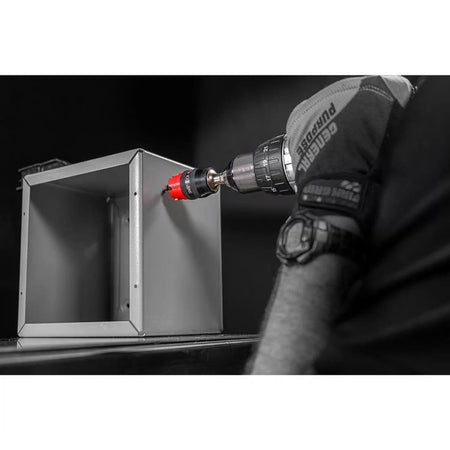A close-up view of a professional worker in safety gloves using a Diablo hole saw and handheld drill to bore a precise hole into a gray metal electrical box.