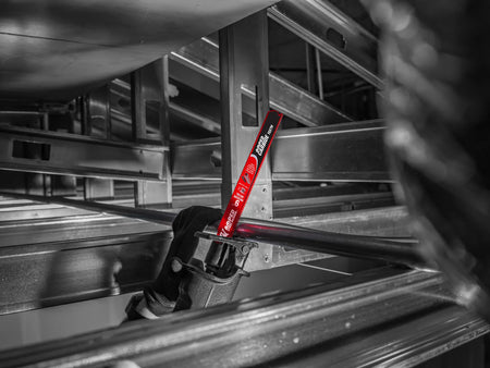 An on-site construction application shot of an operator using a cordless reciprocating saw with a red Diablo AMPED carbide blade to execute a precise, overhead plunge cut through an unistrut metal framing pipe setup.