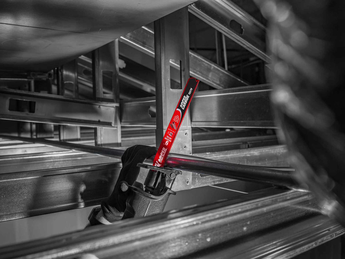 An action photograph of a 9 inch Diablo AMPED Steel Demon carbide blade in a reciprocating saw cutting through an industrial metal pipe in a tight overhead structural space, demonstrating the blade's precision and reach.