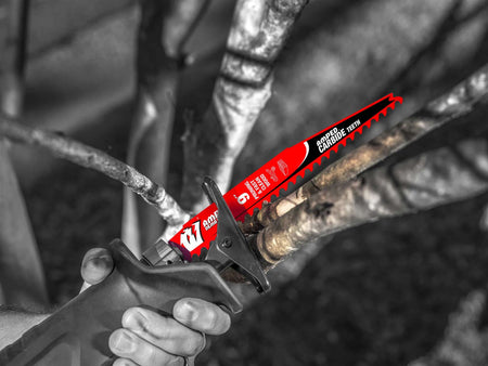 An action photograph of a 9 inch Diablo AMPED carbide pruning blade in a reciprocating saw cutting through a thick tree branch, demonstrating the blade's aggressive 3 TPI tooth geometry and fast material removal in outdoor landscaping tasks.