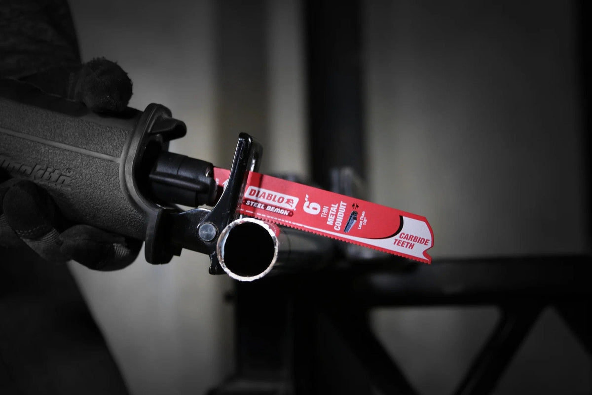 An action photograph of a Diablo Steel Demon carbide blade in a reciprocating saw cutting through a piece of industrial EMT conduit. The image demonstrates the blade's precision and ability to produce clean, burr-free cuts in thin-walled metal tubing.