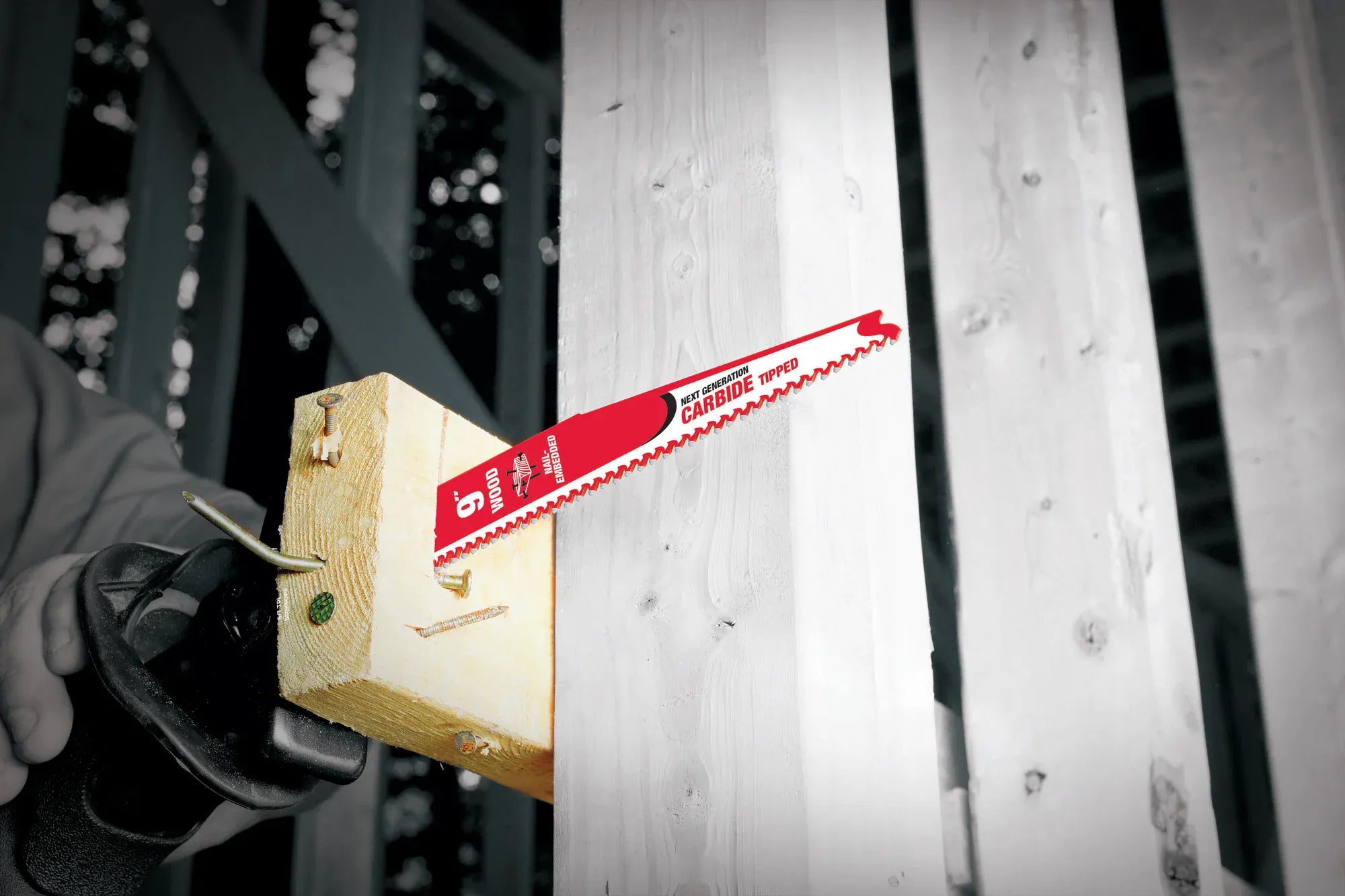 Reciprocating saw equipped with a Diablo carbide tooth blade cutting cleanly through a dense framing stud embedded with nails.