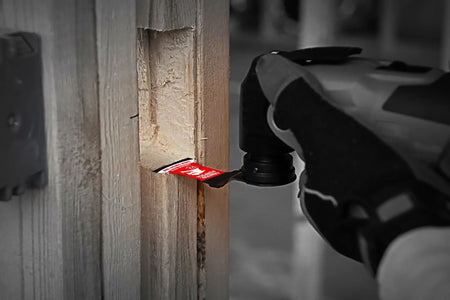 A close-up action photograph of a Diablo carbide teeth oscillating blade performing a plunge cut into a wooden stud.