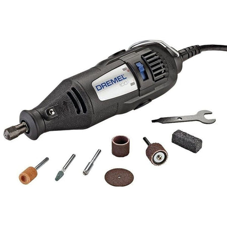 A studio shot of the Dremel 100 Series corded rotary tool, shown with its 7 assorted accessories and the collet wrench on a white background.
