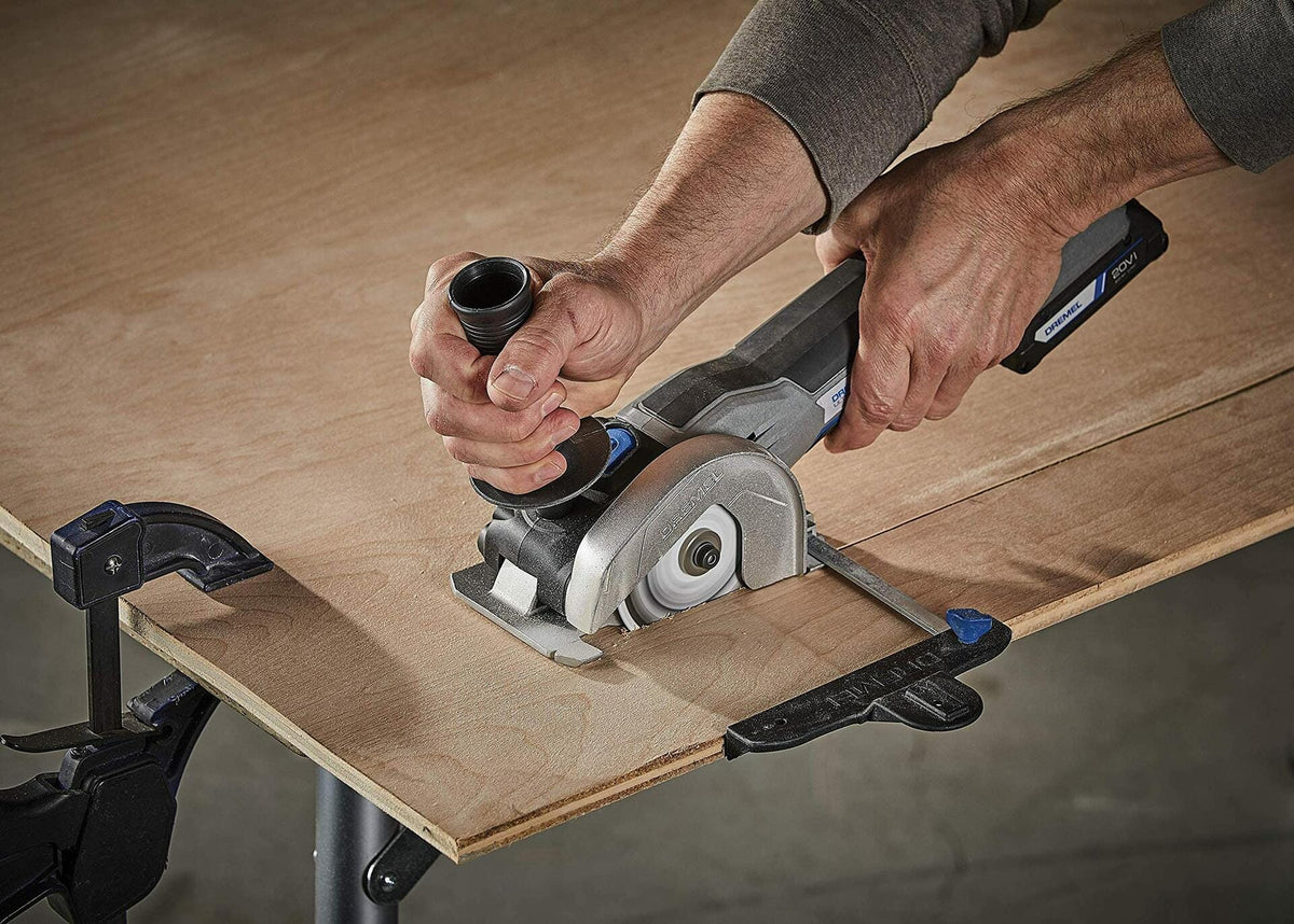 A person using the Dremel cordless ultra-saw with an edge guide to make a precise, straight cut in a sheet of plywood.