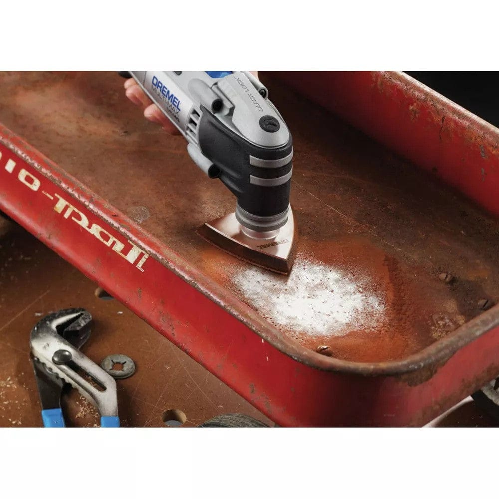A close-up action shot of the Dremel Multi-Max MM40, with its sanding pad attachment, removing rust from the inside of a red wagon.