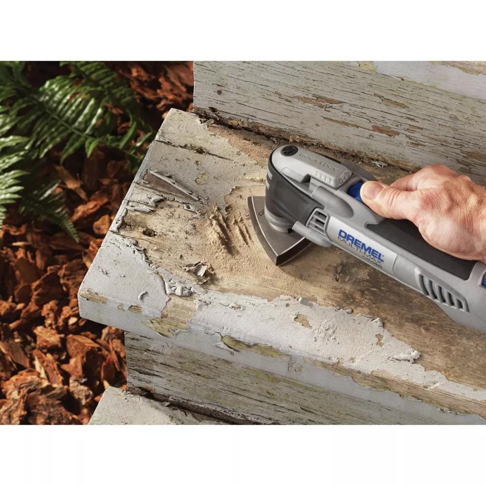 A hand holds the Dremel Multi-Max MM40 tool, using the sanding pad to remove peeling white paint from a wooden step.