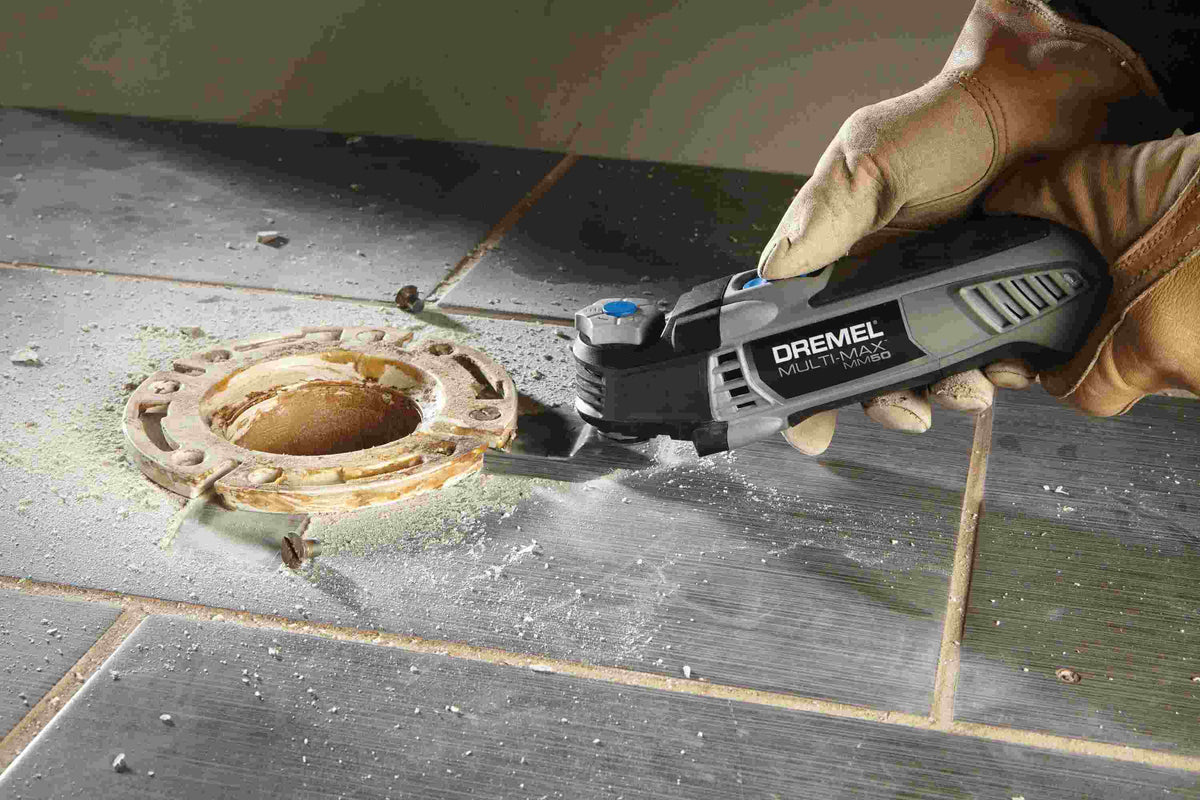 Detailed view of the Dremel MM50 equipped with a metal cutting blade slicing through a thick framing nail embedded in a wooden 2x4 board.