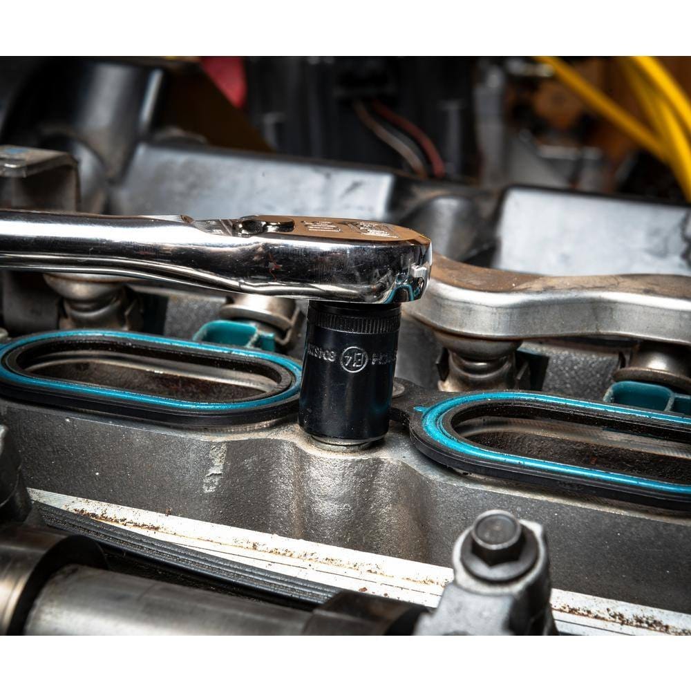 A mechanic using a chrome hand ratchet to loosen a bolt with a black E-Torx socket on a modern engine or housing, highlighting the tight clearance.