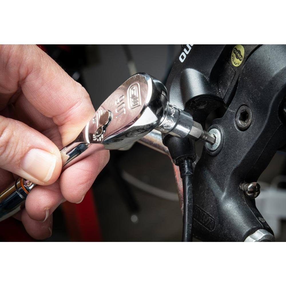 A close-up of a person using a small chrome ratchet and a hex bit socket to tighten a fastener on a bicycle brake lever assembly.