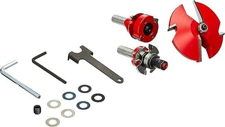 Freud router bit set with three red bits, assorted spacers, hex keys, a wrench, and a small screw. Components are arranged for cabinet door construction and precision adjustment.