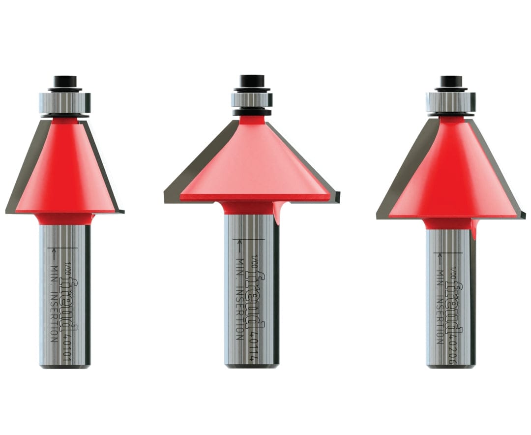 Close-up of three Freud chamfer router bits with red-coated cutting heads and metal shanks. Each bit includes a guide bearing and angled edge for creating beveled profiles on wood surfaces