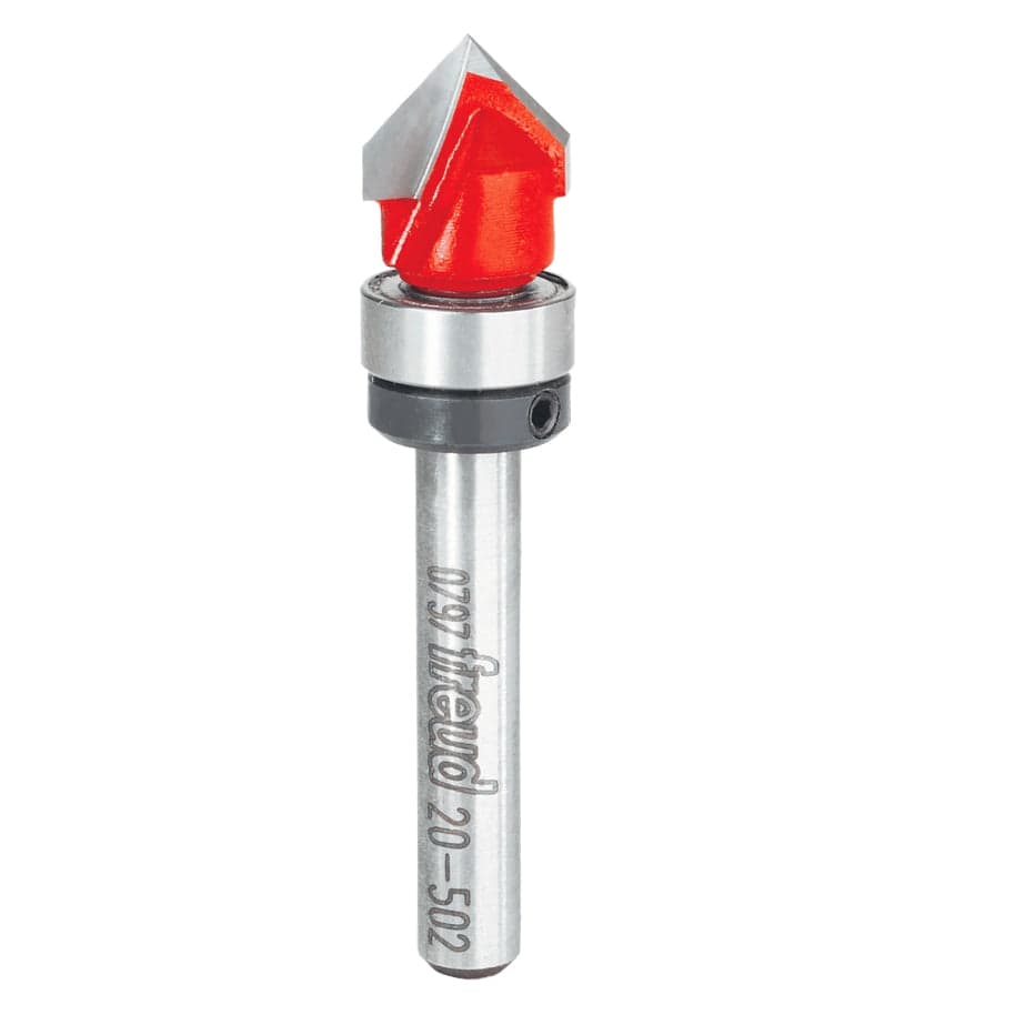 Studio product view of the Freud 20-502 router bit, featuring a 1/4 inch silver shank, a top-mounted ball bearing guide, and a red Perma-SHIELD coated V-shaped cutting head with dual carbide tips.