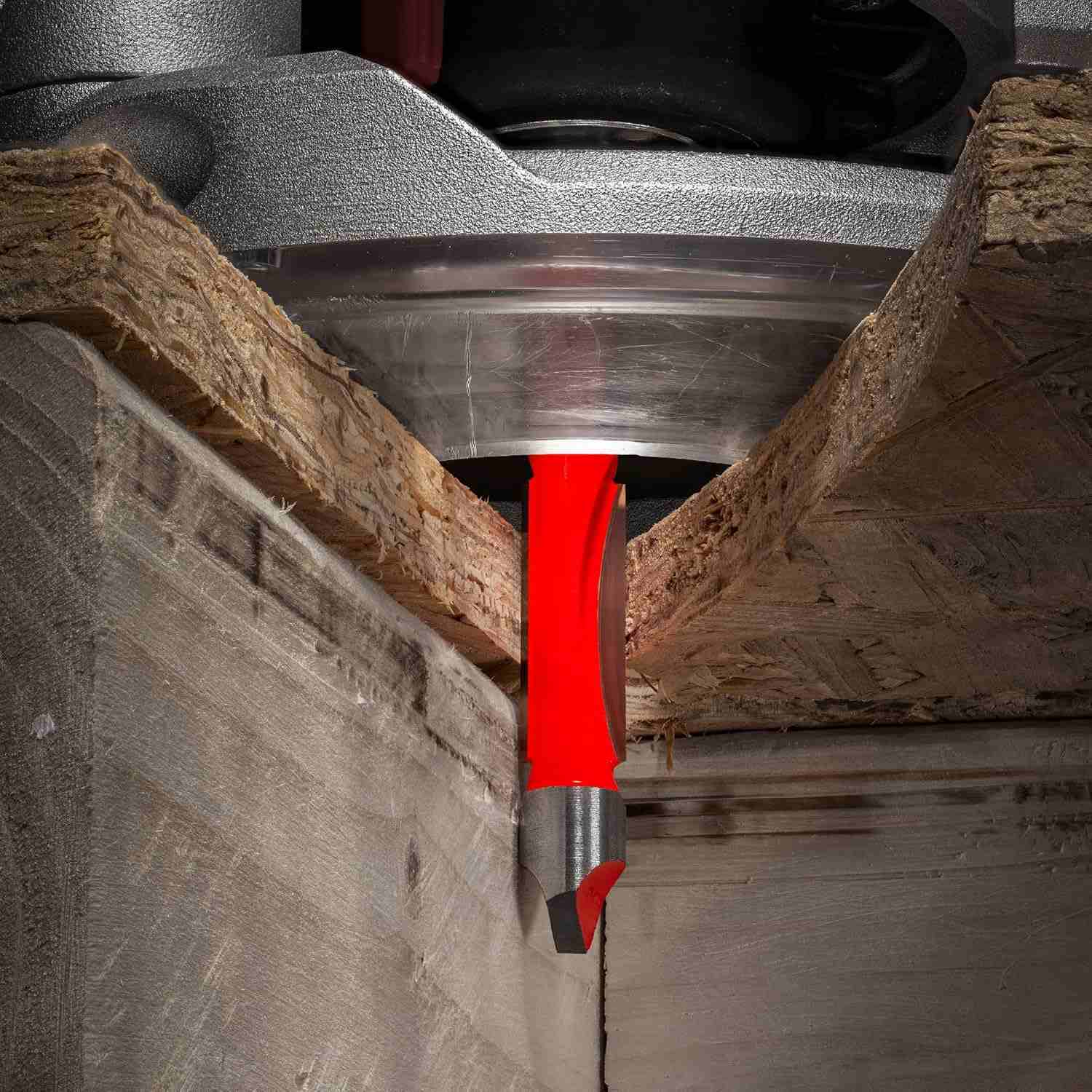 An action-oriented close-up of a Freud panel pilot bit plunging through a composite board, demonstrating its ability to self-start and guide along a template for precise cutouts.