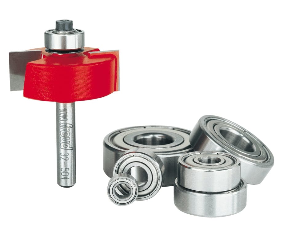 A professional studio photograph of the Freud 32-504 multi-rabbet bit alongside its included accessories, which feature several polished steel ball bearings of varying diameters for adjustable cutting depths.