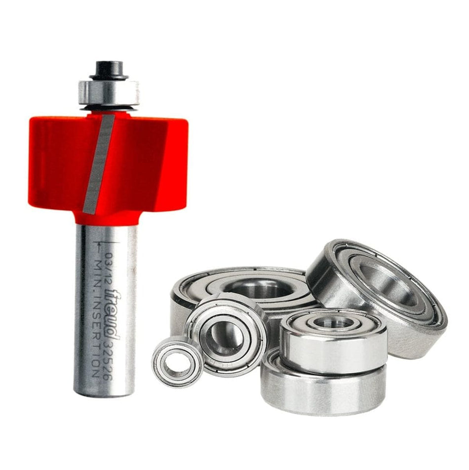A professional studio photograph of the Freud 32-526 multi-rabbet router bit, showcasing its red Perma-SHIELD coating on the cutting head, silver TiCo carbide edges, and a polished 1/2-inch steel shank, shown alongside its included interchangeable ball bearings of various diameters.