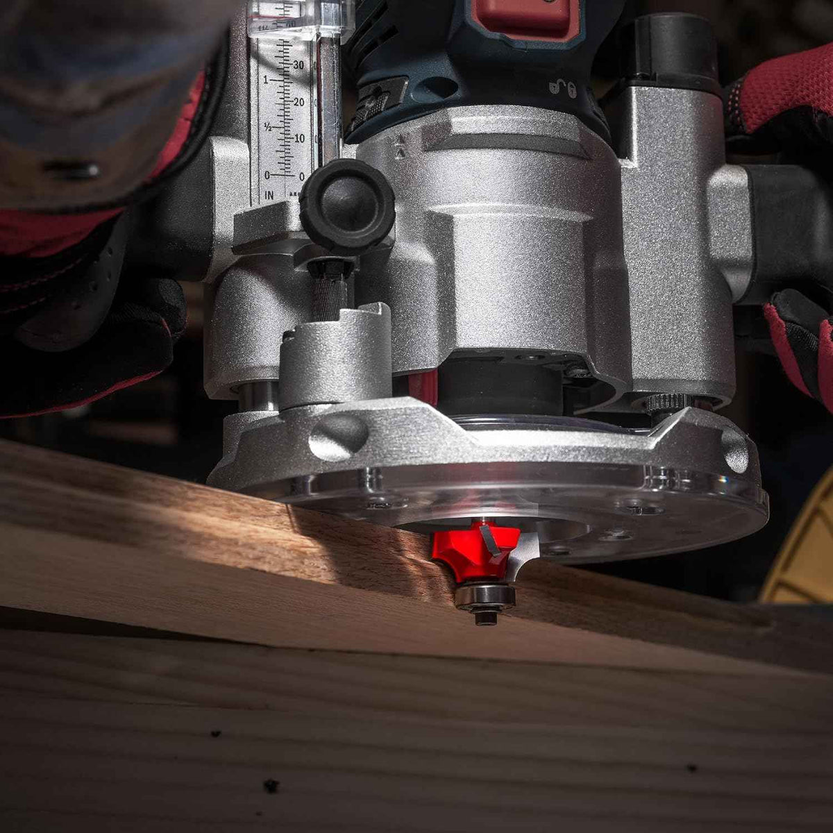 An action-oriented close-up of a Freud rounding over bit mounted in a heavy-duty router, demonstrating the Quadra-Cut technology creating a smooth, rounded edge on a hardwood workpiece.