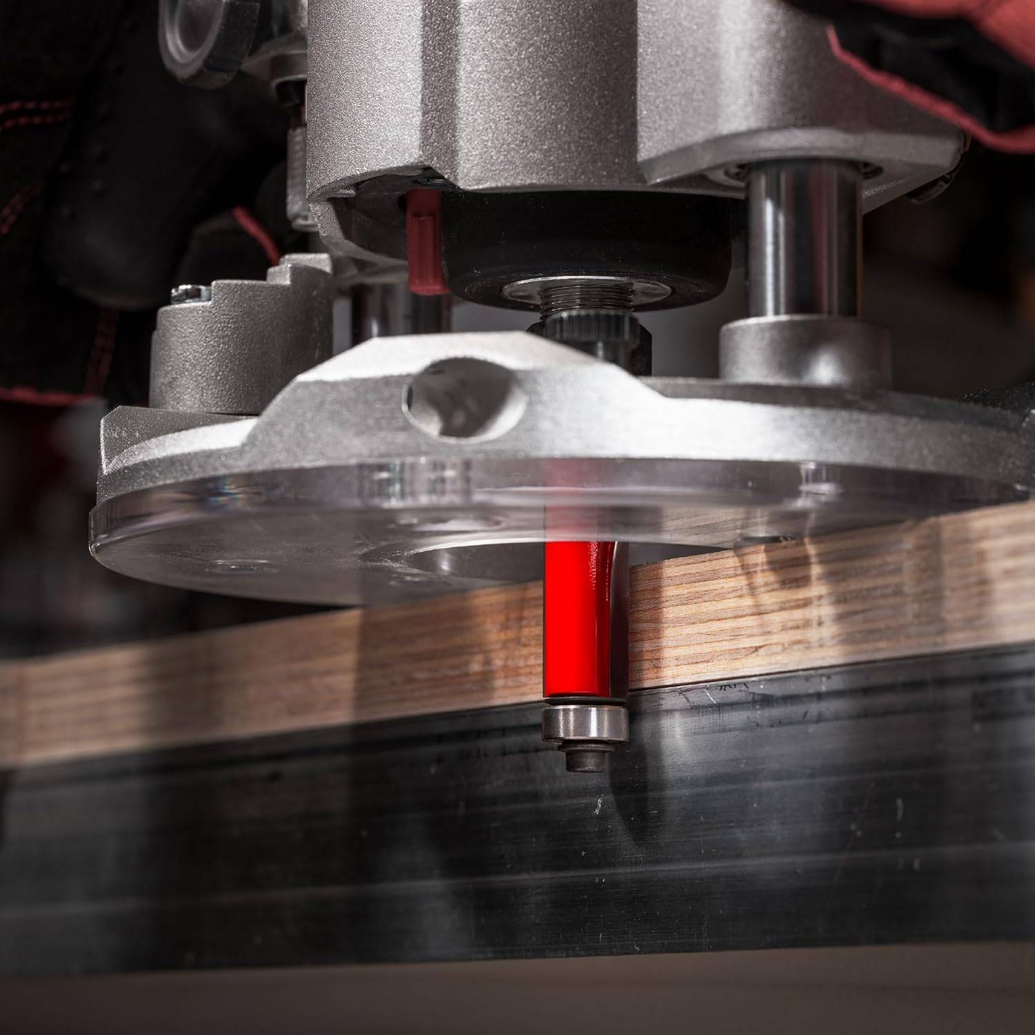Action shot of the Freud 42-110 bearing flush trim bit mounted in a hand-held router, trimming the edge of a plywood sheet flush with a guide.
