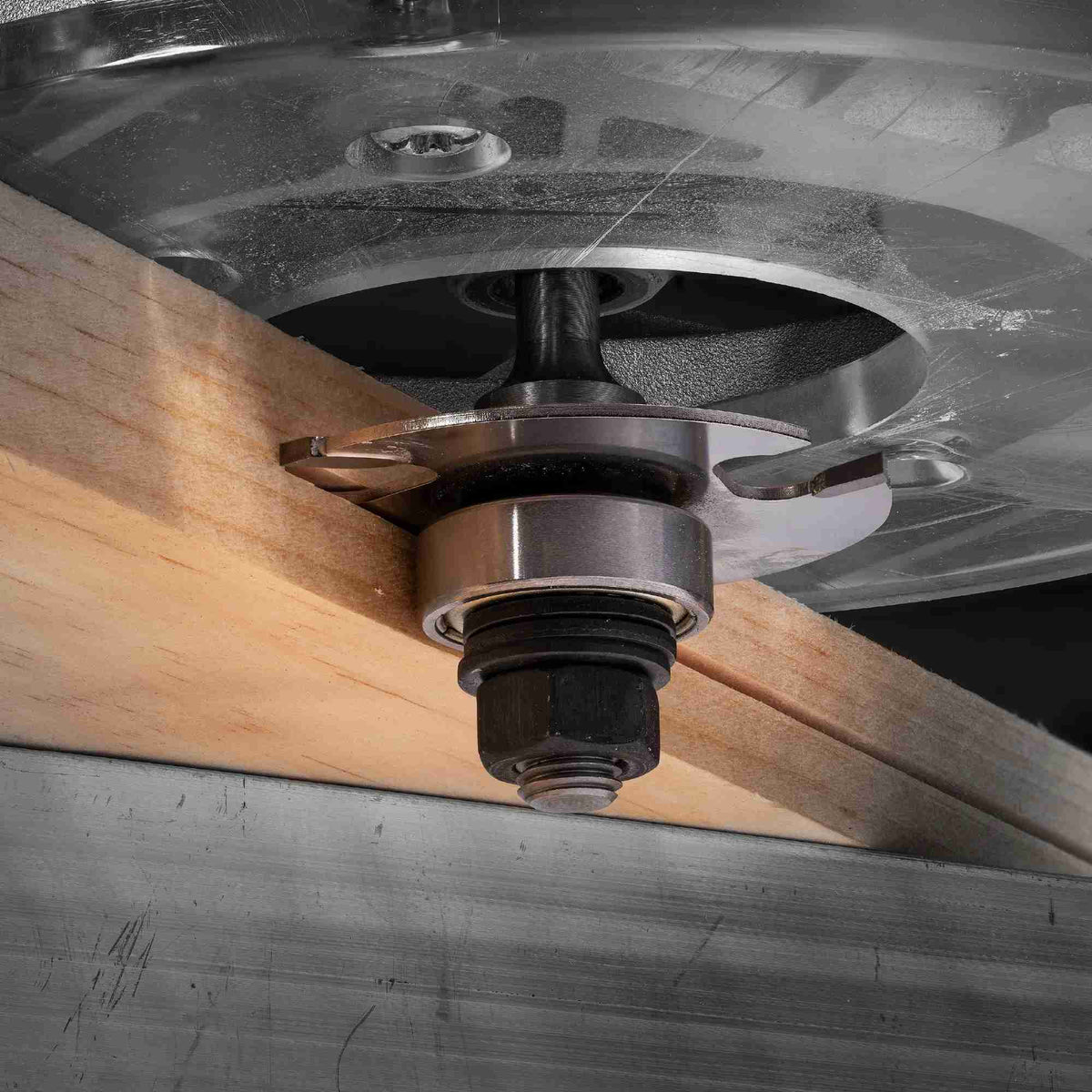 Close-up action shot of the Freud 63-160 three-wing slotting cutter routing a precise, consistent groove into the edge of a wood board using a hand router.