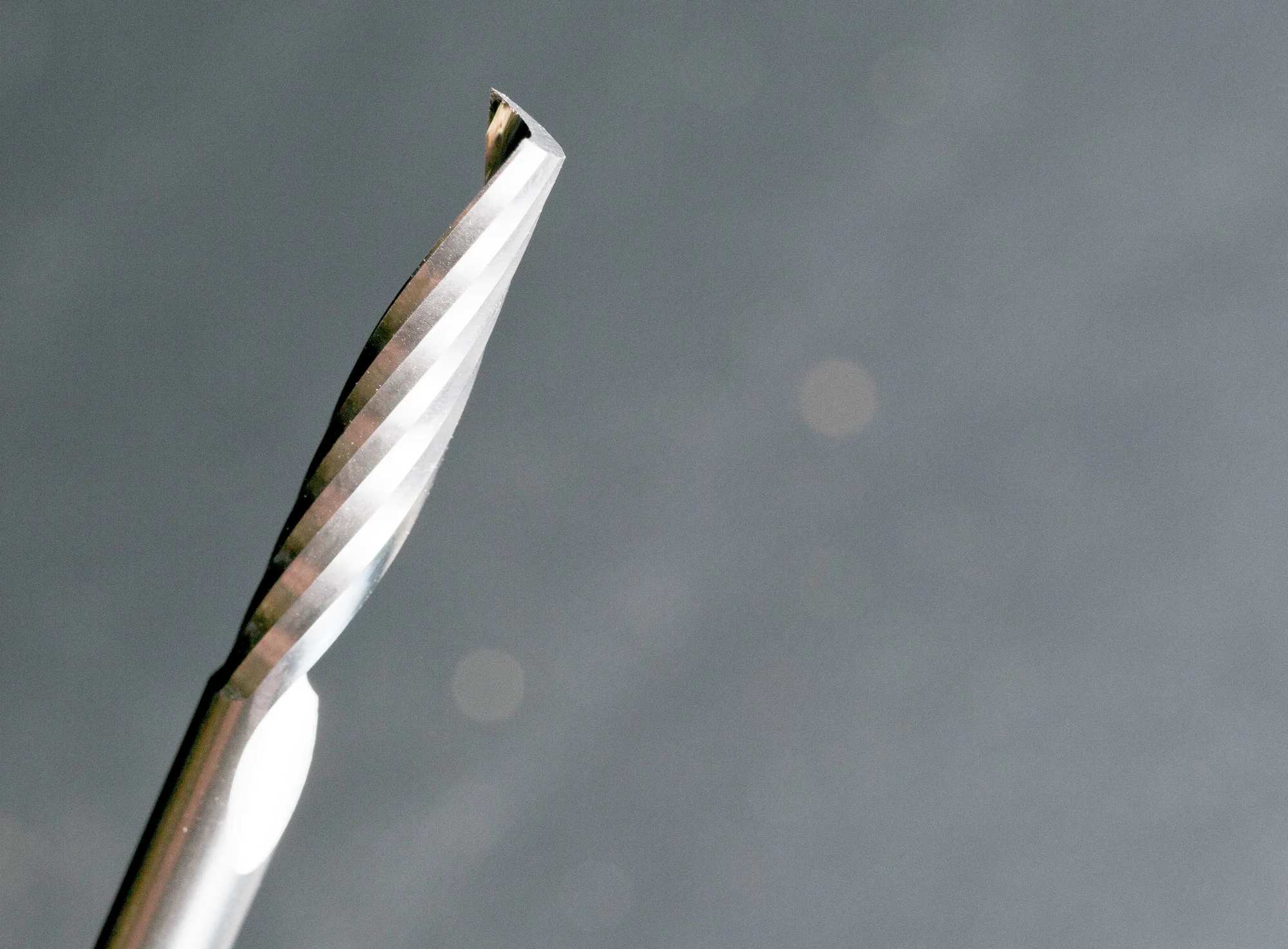 A detailed perspective shot of the spiral cutting edge and the point of the solid carbide O-flute up spiral bit, illustrating the precision engineering for CNC plastic fabrication.