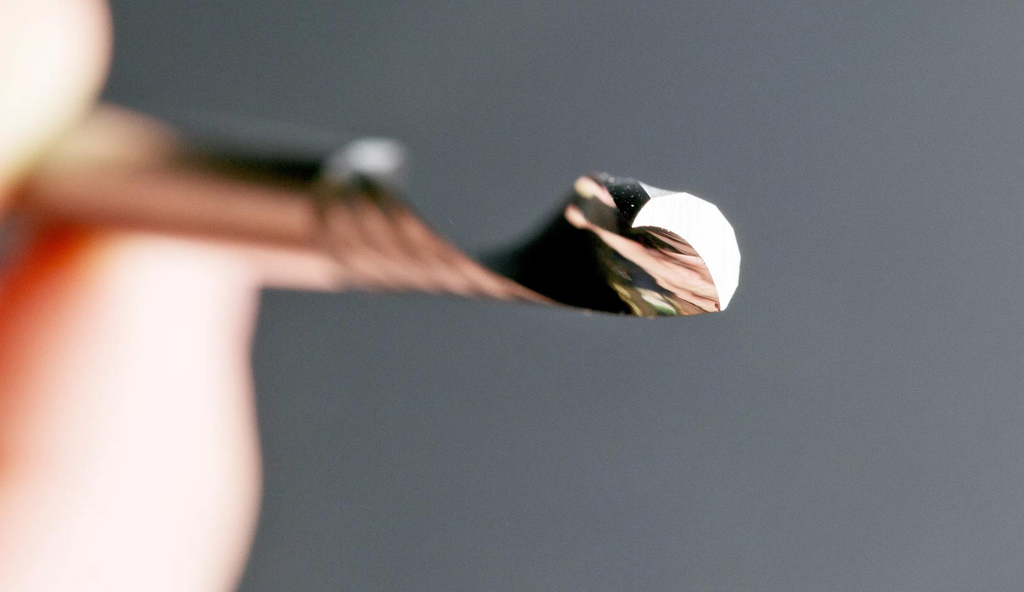 Close-up side view of the sharp cutting edge and spiral geometry of a Freud solid carbide O-flute bit designed for acrylic and ABS.