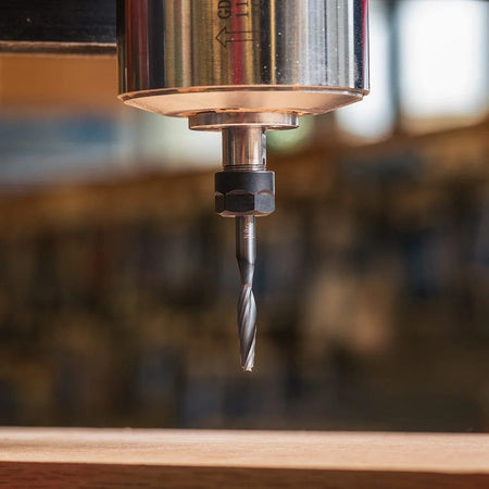 A close-up view of the Freud 1/4-inch up spiral router bit mounted in an industrial router collet, prepared for high-speed mortising and production woodworking.