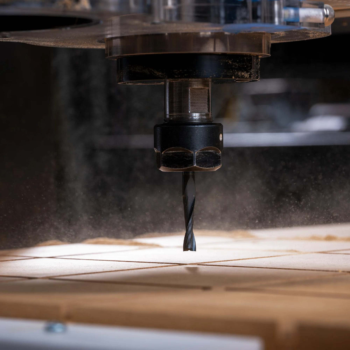 An action shot of the Freud 75-102 1/4-inch solid carbide bit installed in a CNC machine, performing high-precision routing and chip evacuation on a large wood panel.