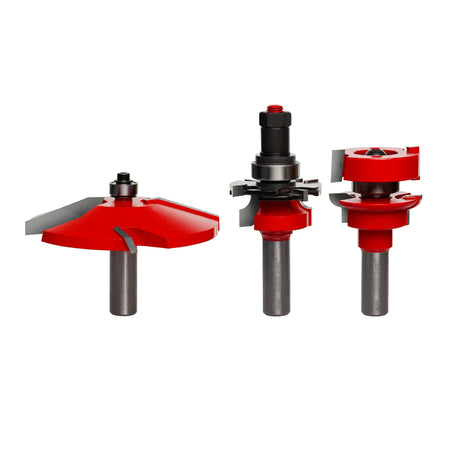A clean studio product shot of the Freud 97-150 3-Piece Premier Adjustable Cabinet Door Router Bit Set over a white background, highlighting the red Perma-SHIELD thermal protective coating, razor-sharp micrograin carbide cutting edges, and unpainted 1/2-inch steel shanks with laser-etched minimum insertion guides, displayed in sequence as the Quadra-Cut cove raised panel profiling bit with an integrated top guide bearing, the adjustable cope rail cutter assembly with adjustable spacing shims, and the matchi