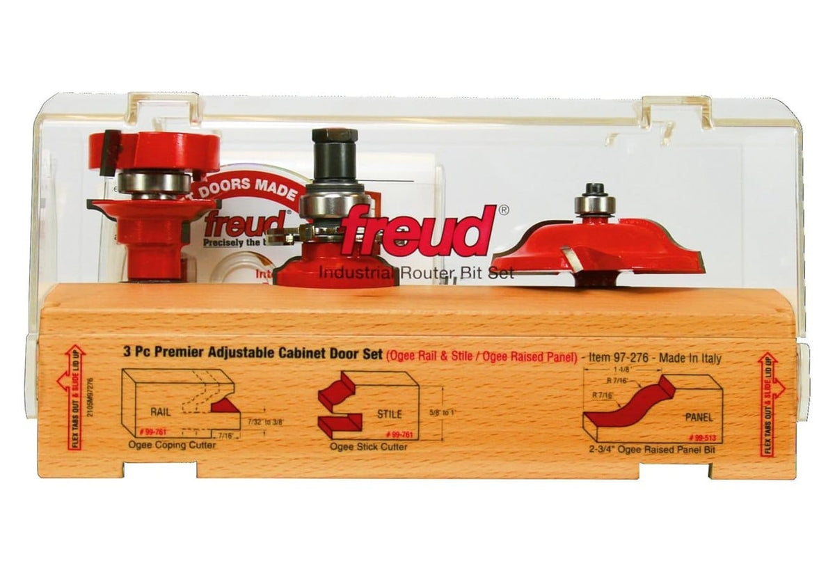 A professional product shot of the Freud 97-276 3-piece premier adjustable cabinet door set featuring red carbide-tipped bits, including an ogee rail and stile bit and a Quadra-Cut raised panel bit, presented in a premium wooden storage case with a technical application diagram.