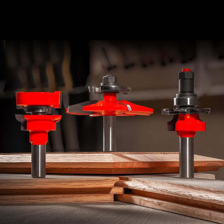 Three Freud adjustable rail and stile bits shown alongside finished wood door components, highlighting the precision joinery and round-over profile.