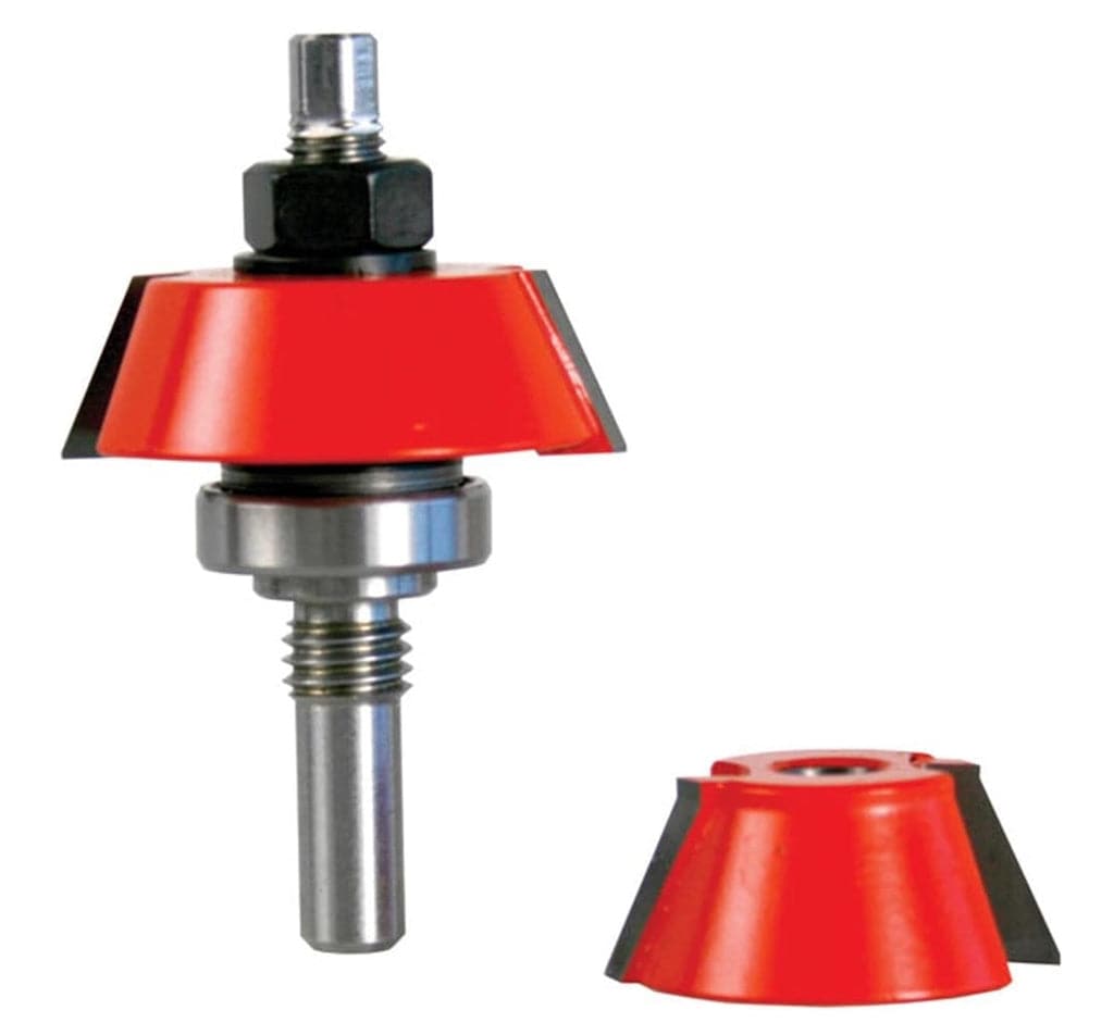 Studio shot of a Freud router bit standing upright, featuring a red body with angled carbide cutters and a top-mounted ball bearing, accompanied by a separate interchangeable cutter head.