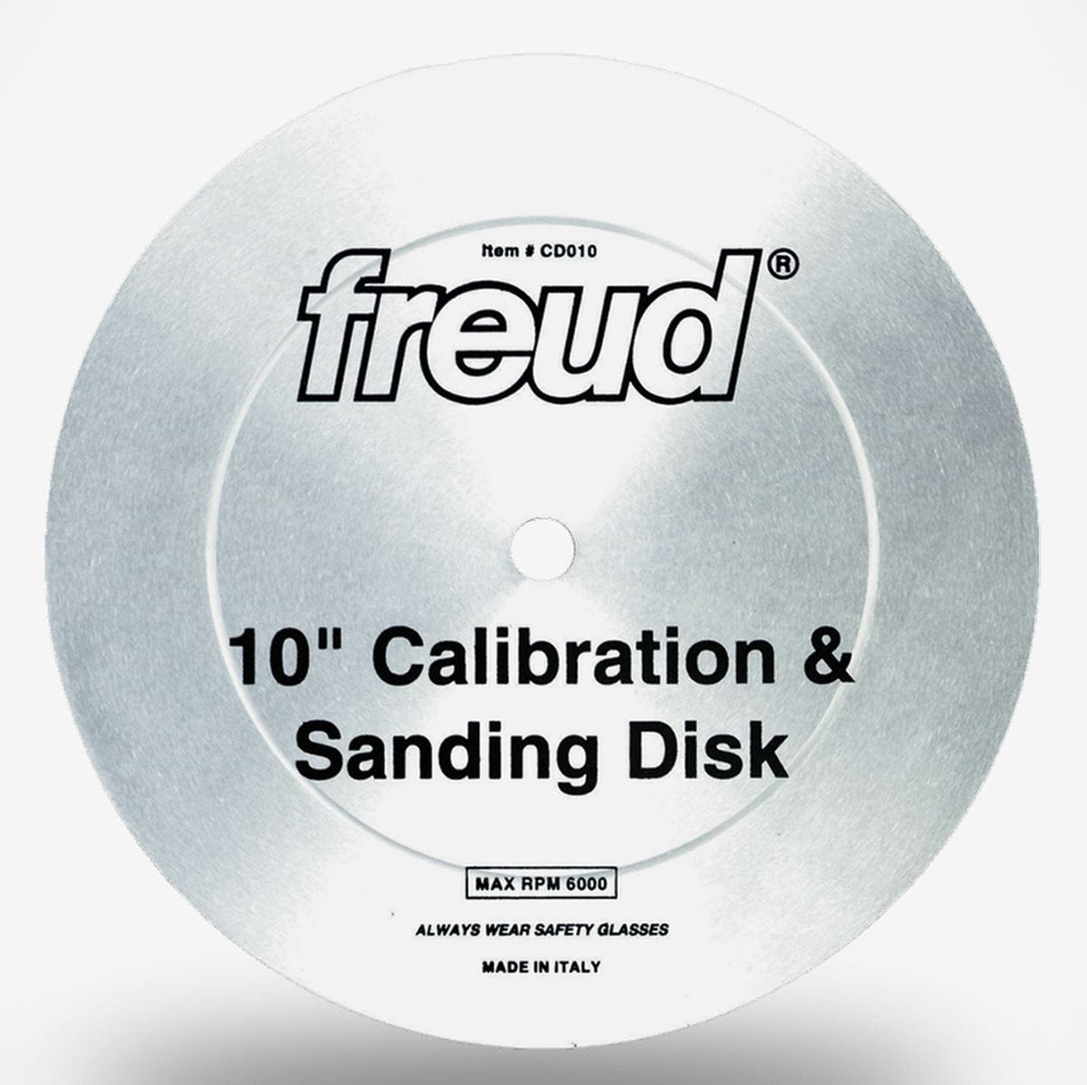 A studio shot of the Freud CD010 10-inch calibration and sanding disc. The silver, toothless metal plate is shown, displaying the Freud logo, its function as a "Calibration & Sanding Disk," and its 6000 max RPM rating.