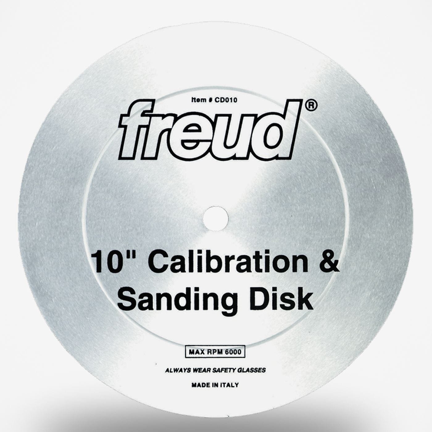 A studio shot of the Freud CD010 10-inch calibration and sanding disc. The silver, toothless metal plate is shown, displaying the Freud logo, its function as a "Calibration & Sanding Disk," and its 6000 max RPM rating.