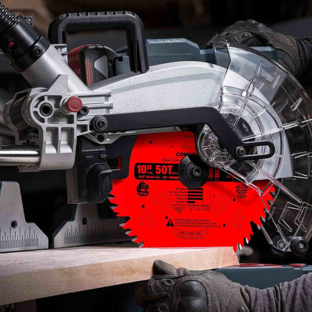 Action shot of a Freud industrial circular saw blade mounted on a sliding compound miter saw performing a precise crosscut on a thick hardwood timber board.