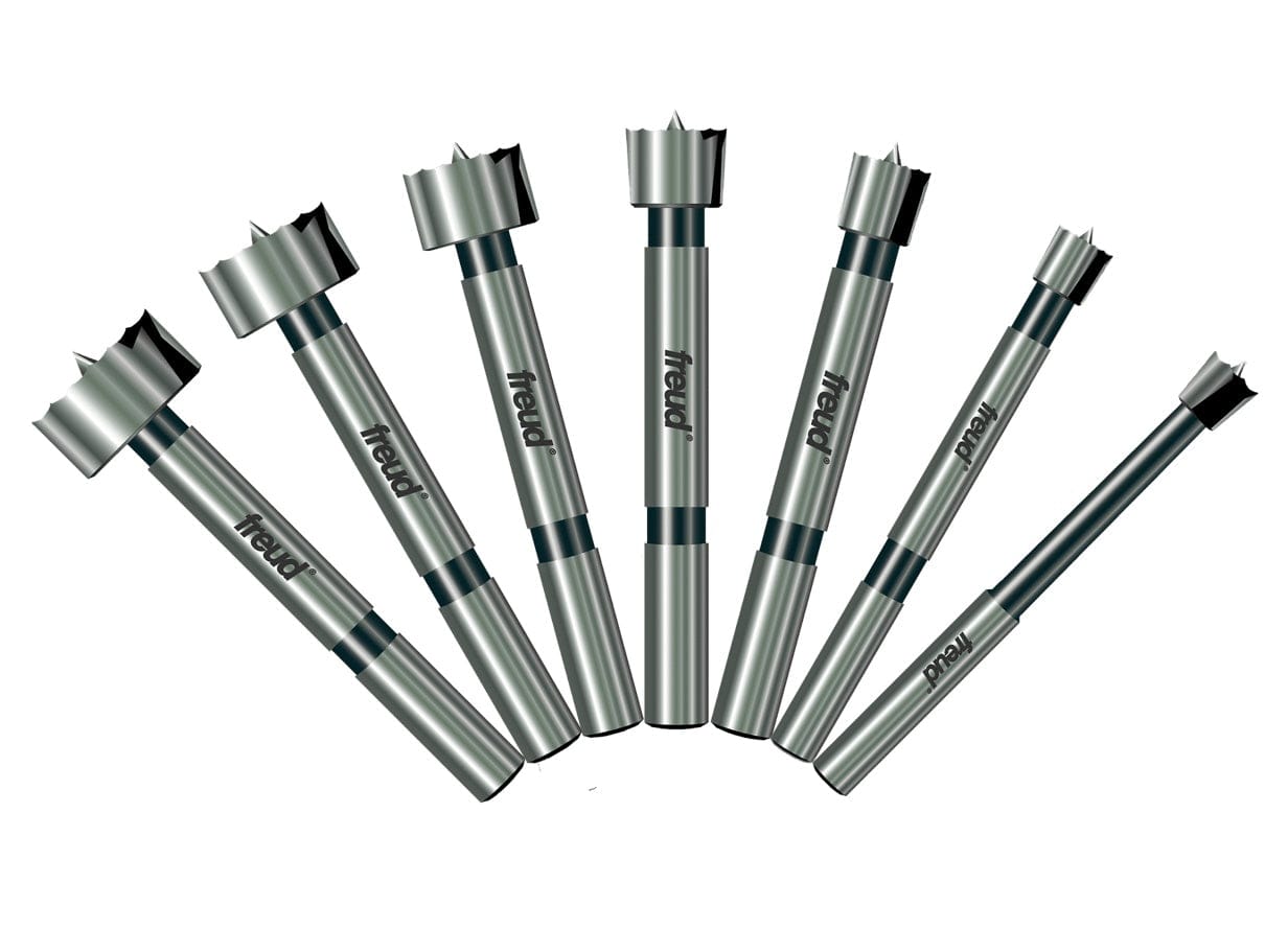 A professional product illustration of the seven carbide Forstner bits included in the Freud PB-107B set, displayed in a fan arrangement to show the progression of sizes from 1/4 inch to 1 inch.