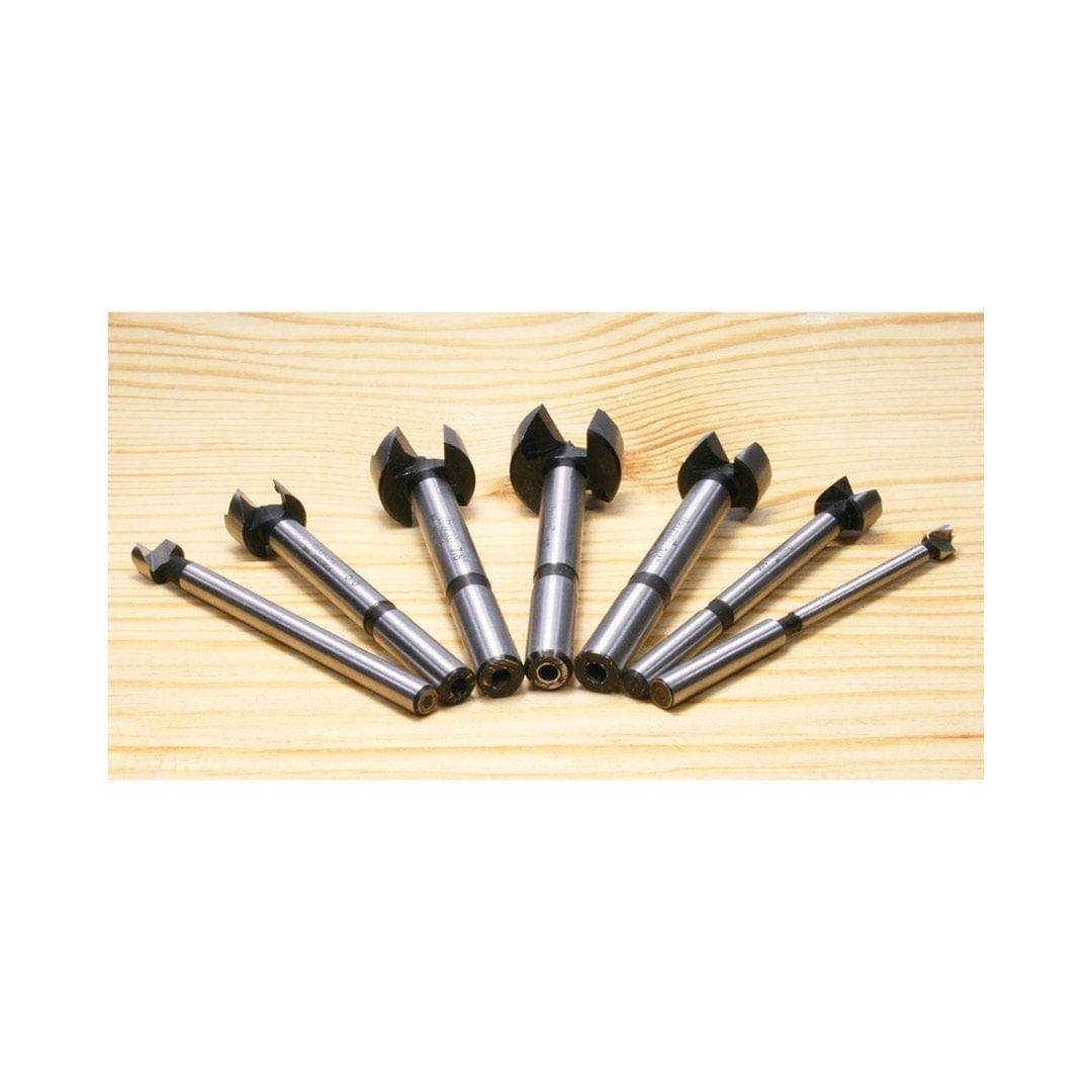 A fan layout of the Freud PB-107B Forstner bits on a wooden surface, showcasing the black-finished cutting heads and polished shanks for professional woodworking applications.