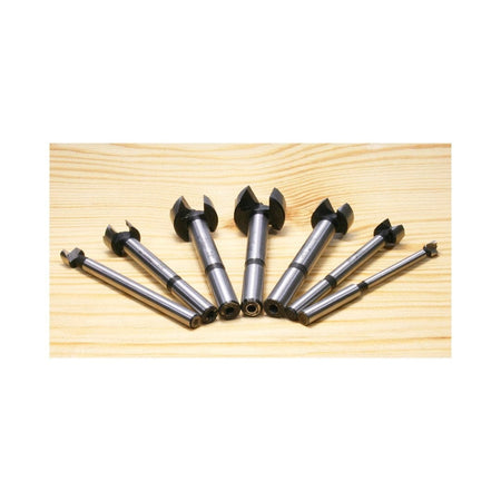 A fan layout of the Freud PB-107B Forstner bits on a wooden surface, showcasing the black-finished cutting heads and polished shanks for professional woodworking applications.