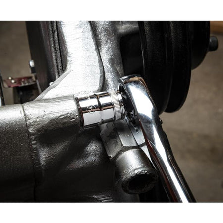 A ratchet wrench engaged with a bolt on a metallic engine component. The socket fits securely over the bolt head, illustrating practical use of the GEARWRENCH socket set in mechanical or automotive repair.