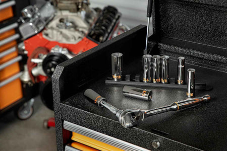 An authentic workshop view of GEARWRENCH deep chrome sockets standing on an orange organizer rail next to a 90-tooth teardrop ratchet handle on top of a black tool cabinet slider tray.