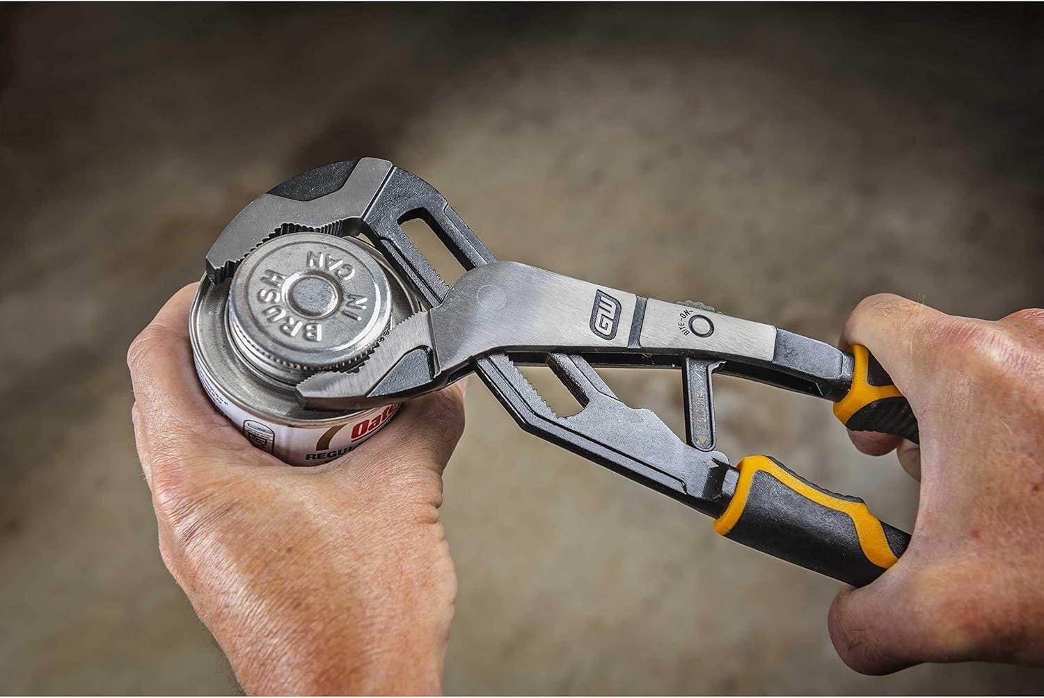 A close-up view of a professional using the GEARWRENCH PITBULL Auto-Bite tongue and groove pliers to grip a thick metal pipe, demonstrating the secure bite of the V-jaw design in a mechanical setting.