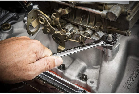 Close-up of a person using a chrome combination wrench to adjust a bolt on a clean engine component. The mechanical assembly includes linkages and fasteners, illustrating real-world automotive use.