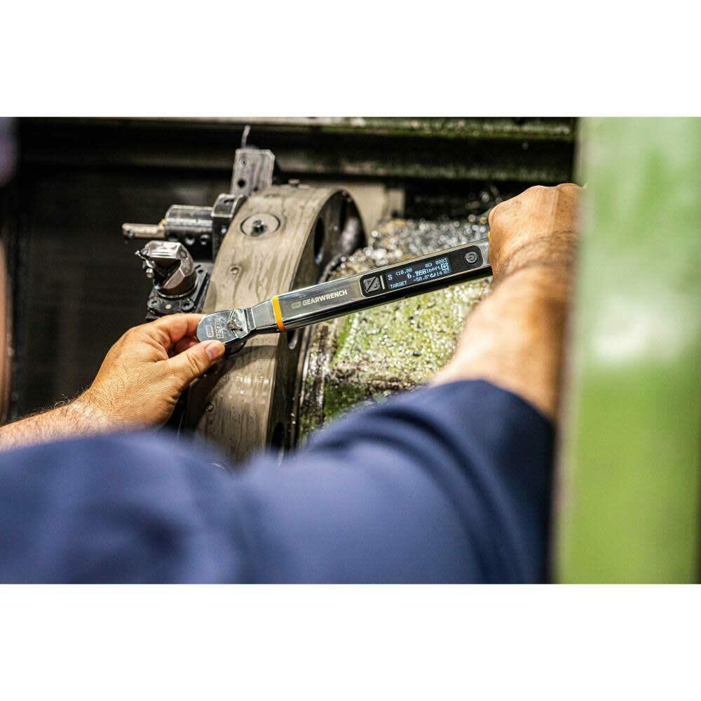A worker using the GEARWRENCH E-Spec electronic torque wrench to fasten a component on a large, oiled piece of machinery, showing the digital screen clearly.