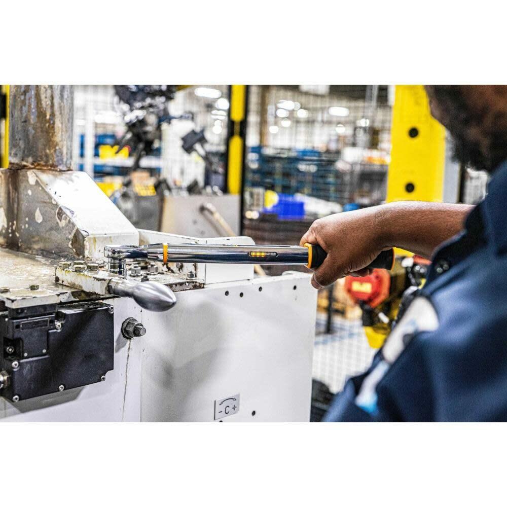 A factory worker using the GEARWRENCH E-Spec electronic torque wrench to tighten a bolt on heavy machinery, with the digital display visible on the tool's handle.