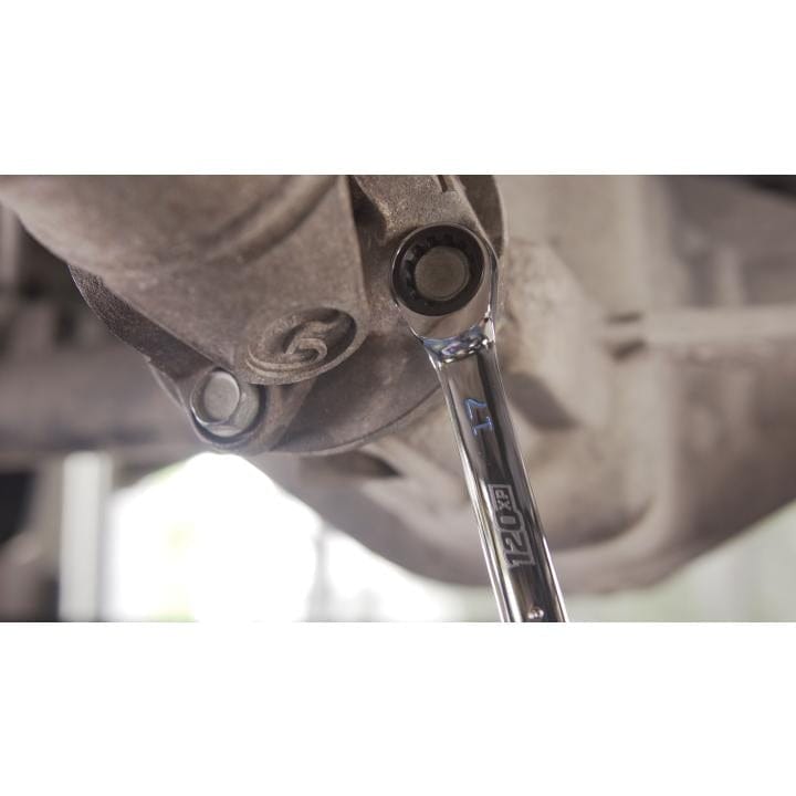 A close-up shot underneath a vehicle, showing a chrome 120XP universal spline ratcheting wrench engaging a bolt on an aluminum differential or housing.