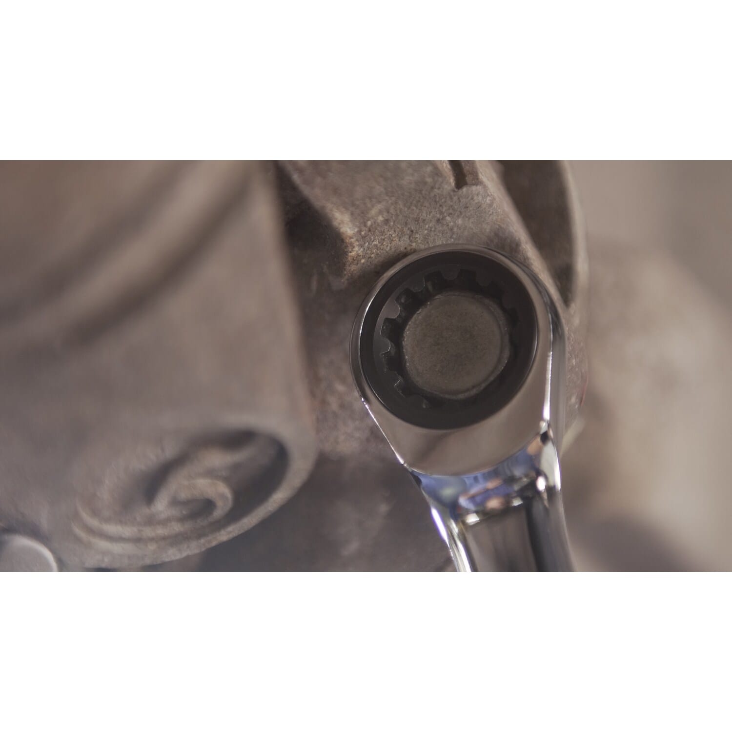 A detailed close-up shot showing the ratcheting box end of a GEARWRENCH 120XP wrench engaged with a bolt head on heavy industrial machinery.