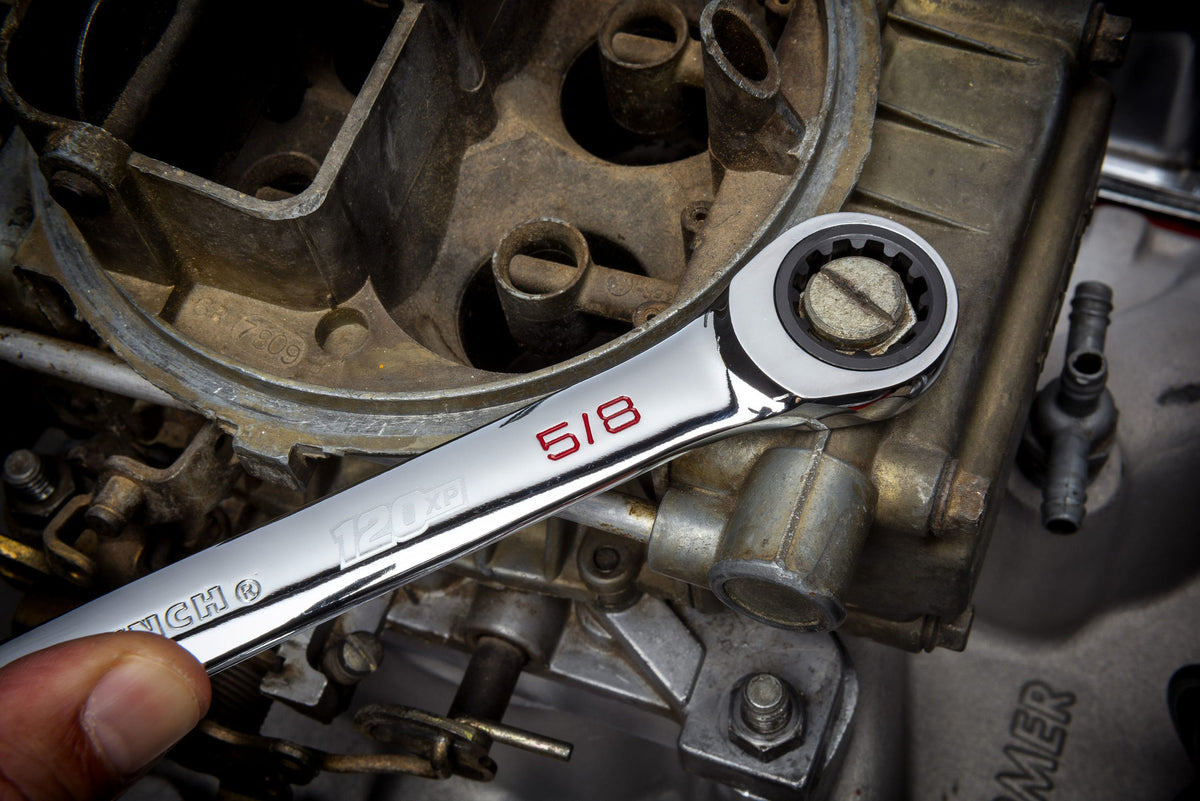 An automotive application shot showing a technician using the 5/8 inch ratcheting box end of a GEARWRENCH 120XP XL wrench to adjust a fastener on an engine's intake manifold.