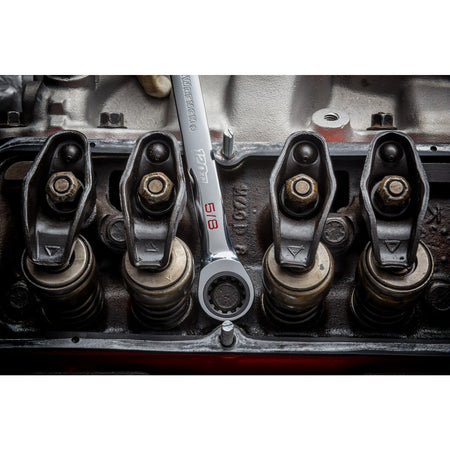 An overhead detail shot of a technician using a 5/8 inch GEARWRENCH 120XP XL ratcheting wrench, with the open end engaged on a rocker arm bolt inside an opened high-performance V8 engine block.