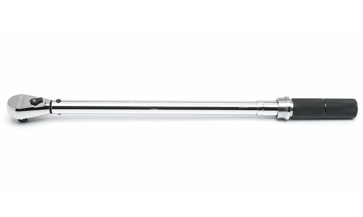 This image shows a long, chrome-plated torque wrench laid horizontally against a white background. The right end features a textured black grip, while the left end has a ratchet head with a small black lever.

