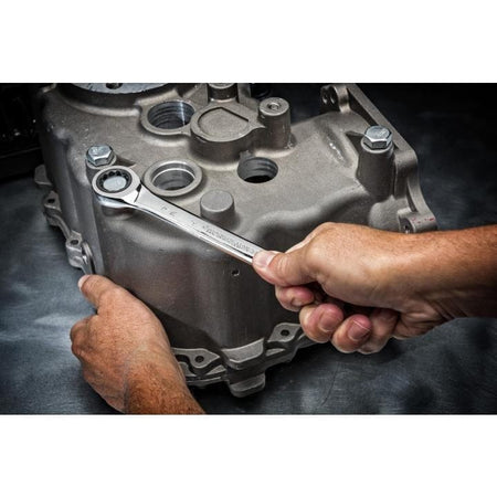 A person using a chrome 72-tooth GEARWRENCH ratcheting combination wrench to tighten a bolt on a large aluminum engine case.