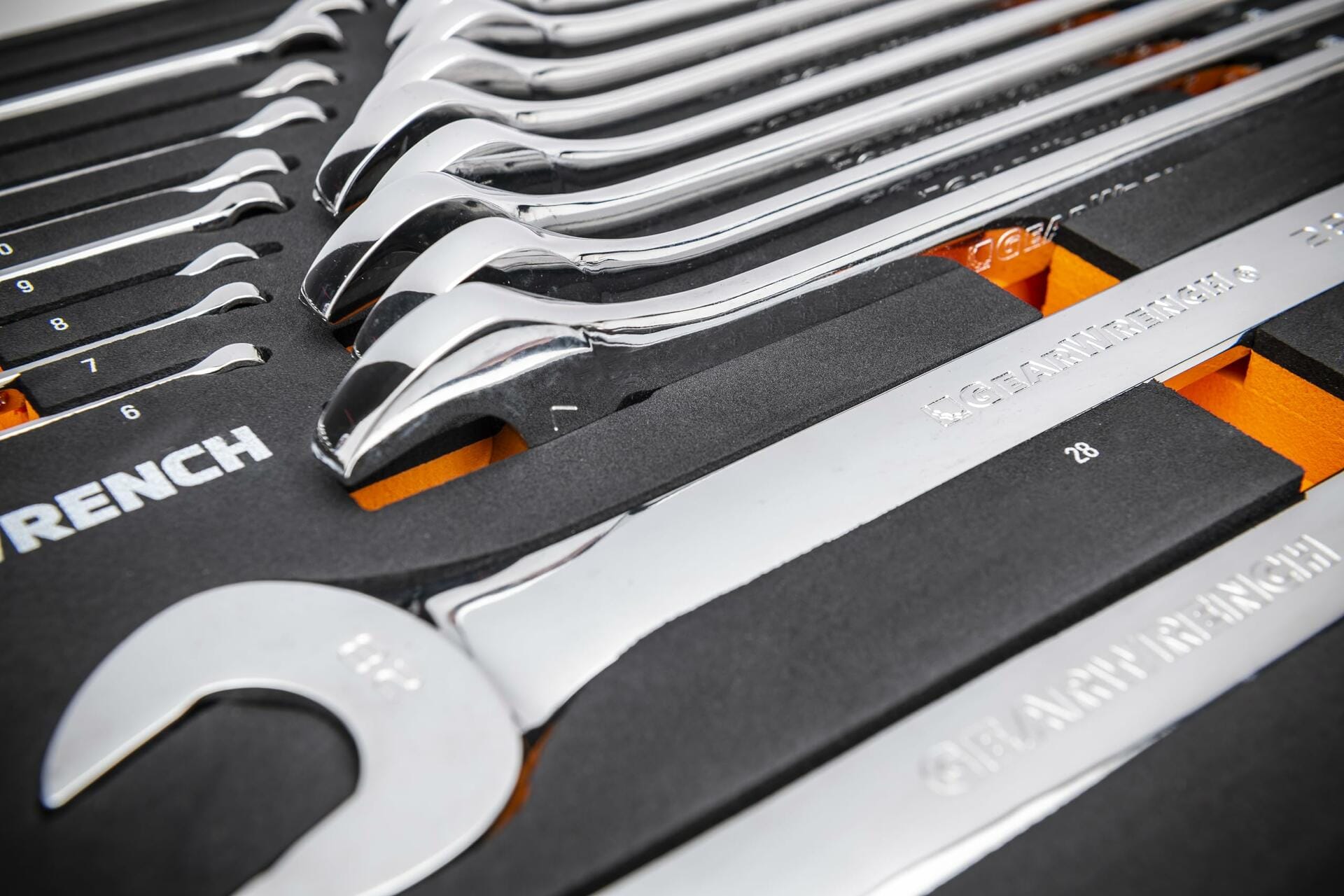 GEARWRENCH 24-piece metric combination wrench set organized in foam tray; chrome wrenches arranged in ascending order from 6mm to 29mm with labeled slots and orange highlights.